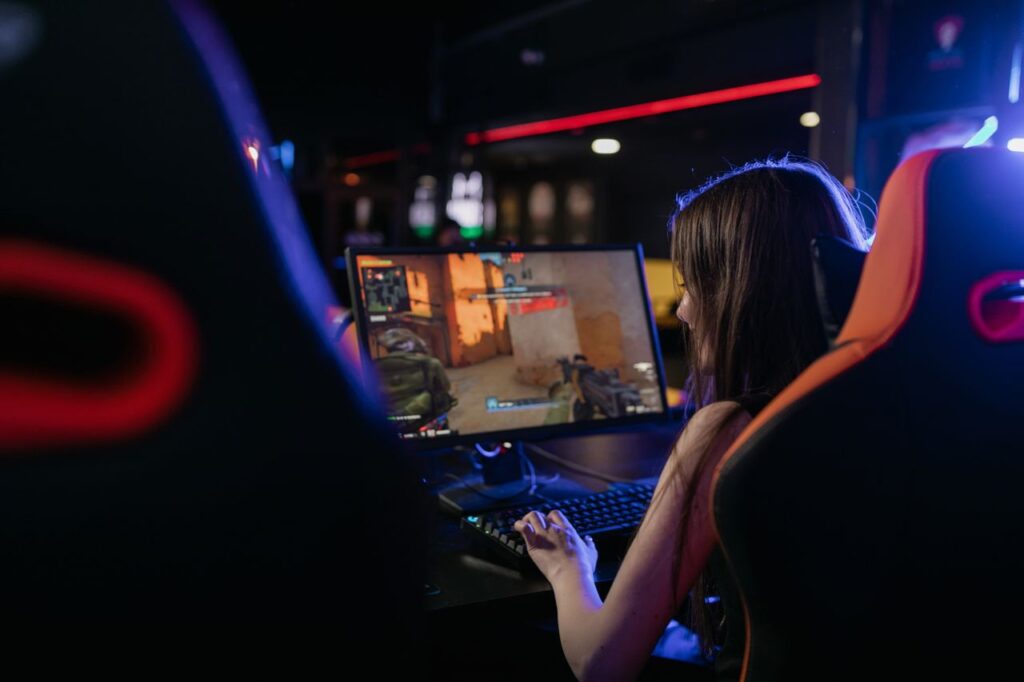 Como saber se o PC Gamer roda seus jogos? (PC Gamer Check) A woman is deeply engaged in playing computer games indoors, highlighting the gaming lifestyle.